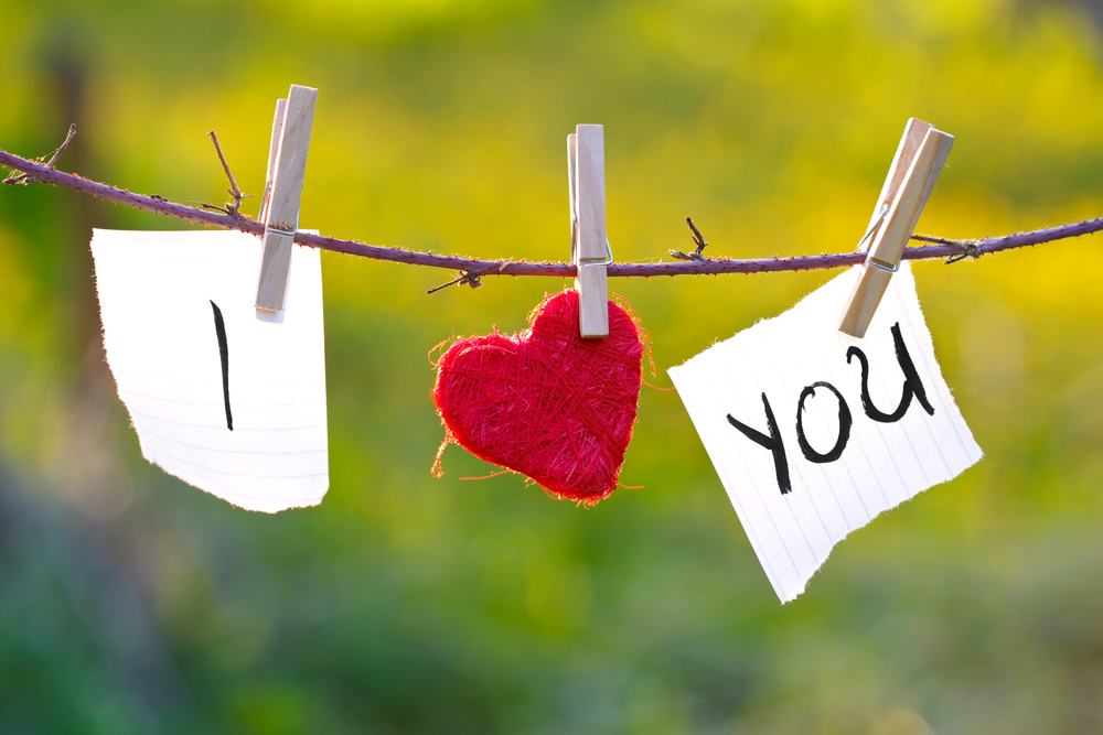 The original composition of the message I love you. A composition of hearts hanging on a rope and pieces of paper with words of love.